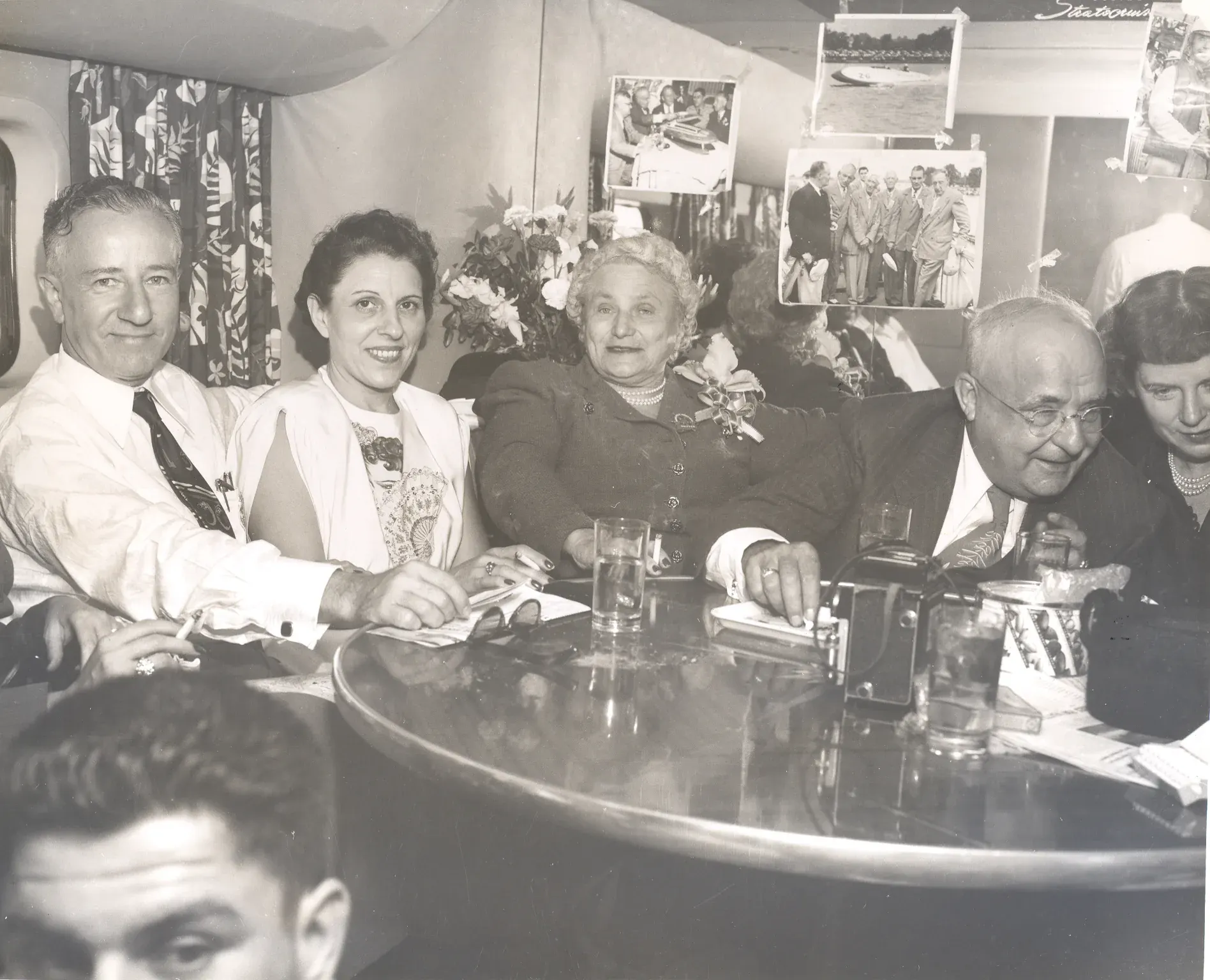 Guests around a table aboard the Stratocruiser flying to Seattle for the 1955 Gold Cup, Mrs. Dodge seated at the center with a corsage.
