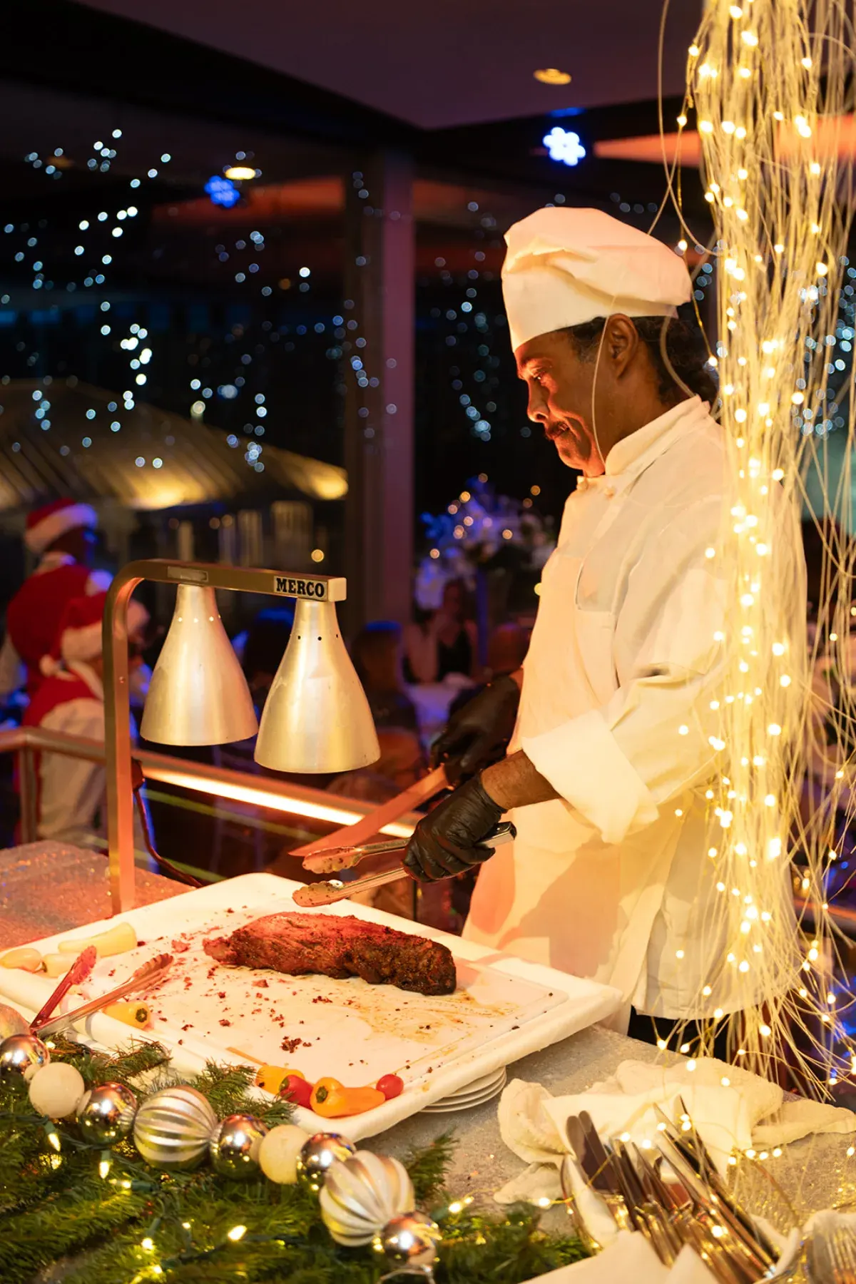 Our chef carving at a holiday party station under cascading string lights