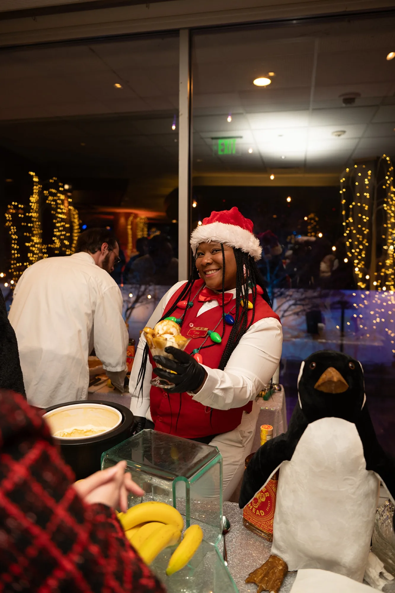 A server in a Santa hat plating dessert at a holiday party buffet
