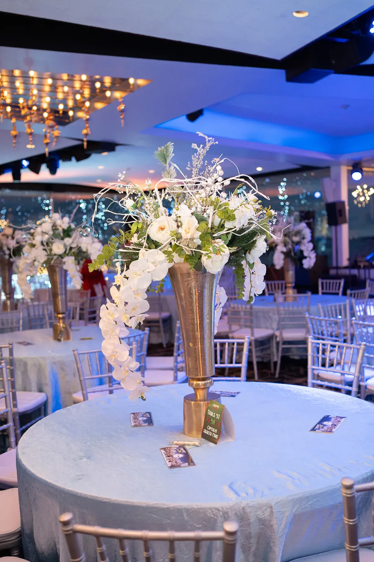 Gold and white orchid tablescape under the chandeliers at a company holiday party