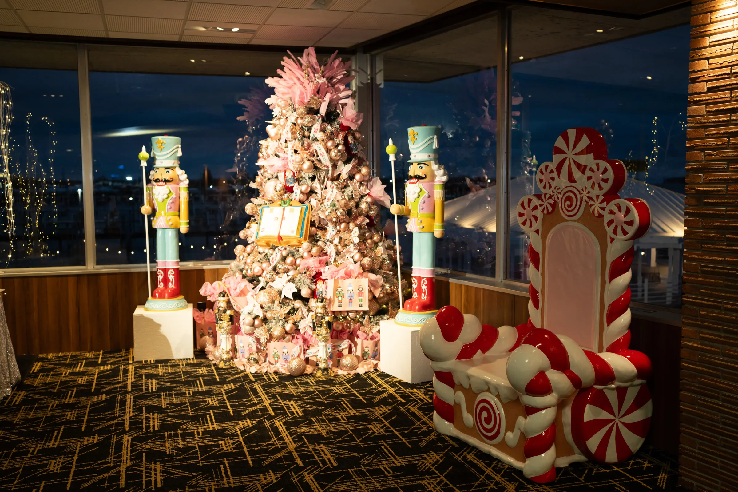 A pink Christmas tree flanked by nutcrackers in front of the river windows
