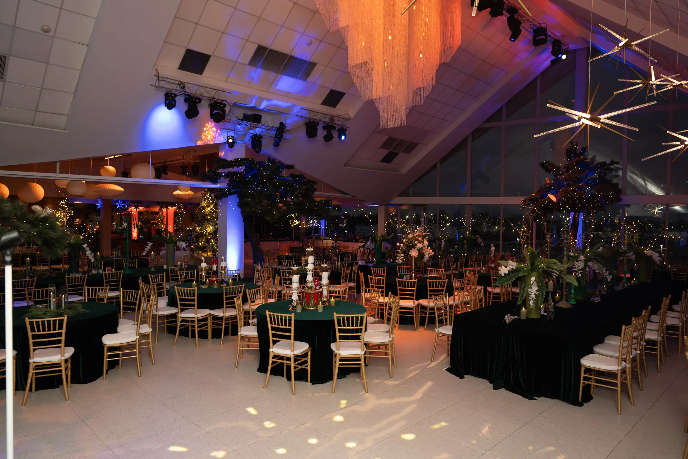 A ballroom set for a corporate holiday dinner, rounds with tall gold centerpieces