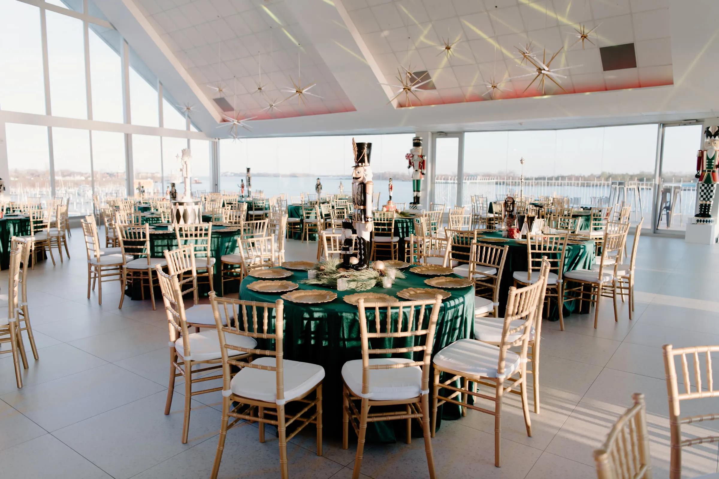 The Palm River Room set with emerald rounds and gold chairs in daylight, the river through the windows