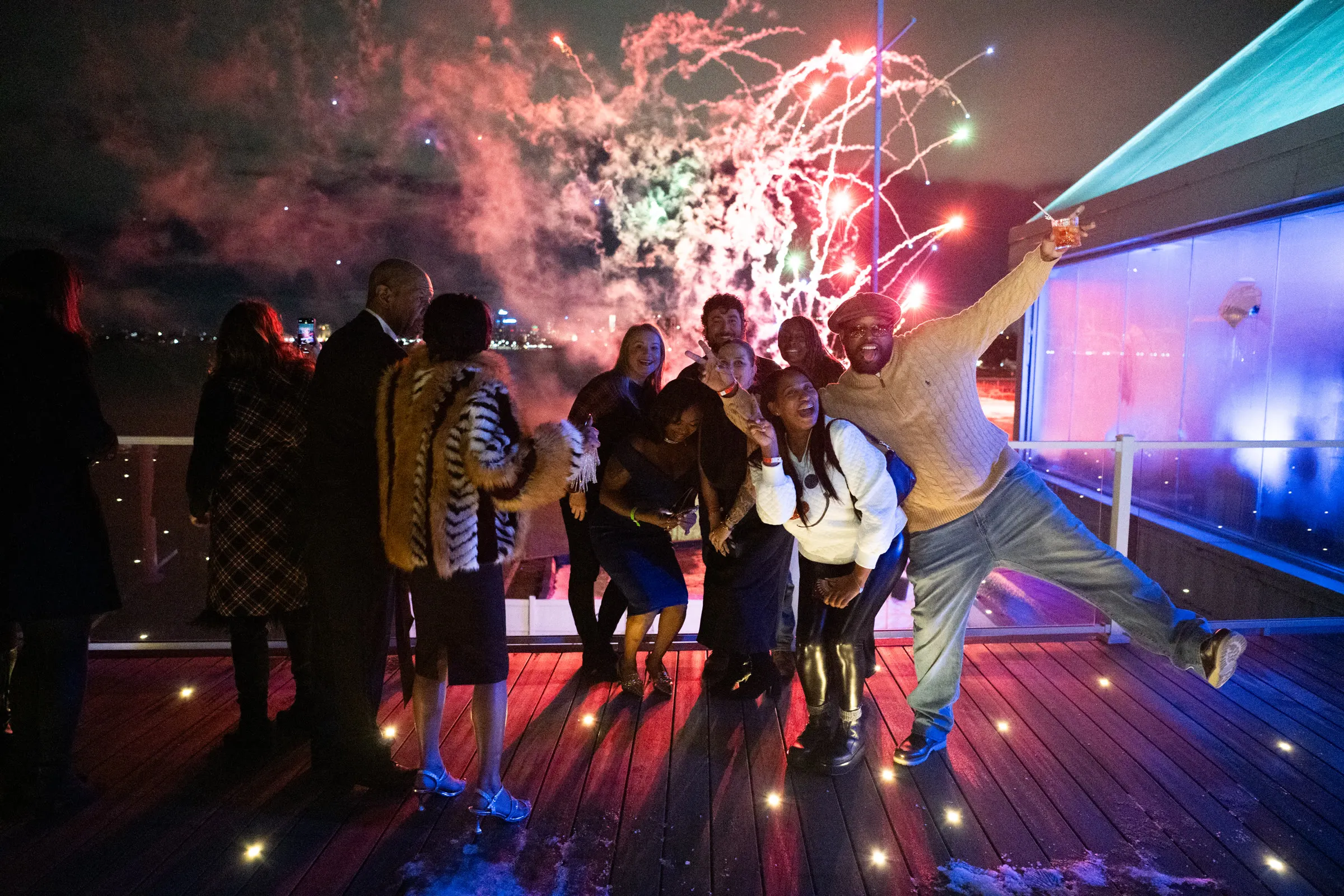 Guests on the deck with fireworks going off over the river