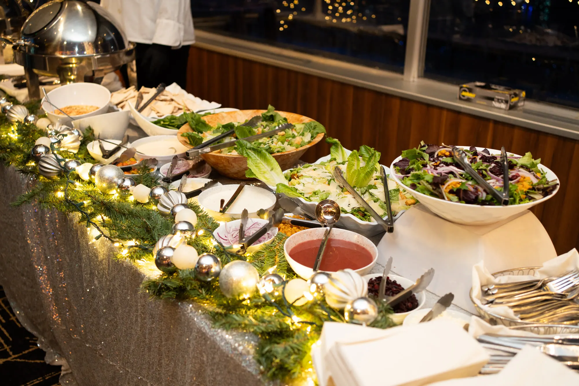 A salad buffet dressed with garland and lights at a Roostertail event